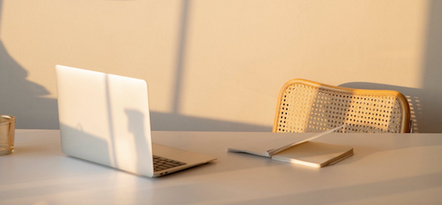 computer at desk with notebook and pen and ambient lighting