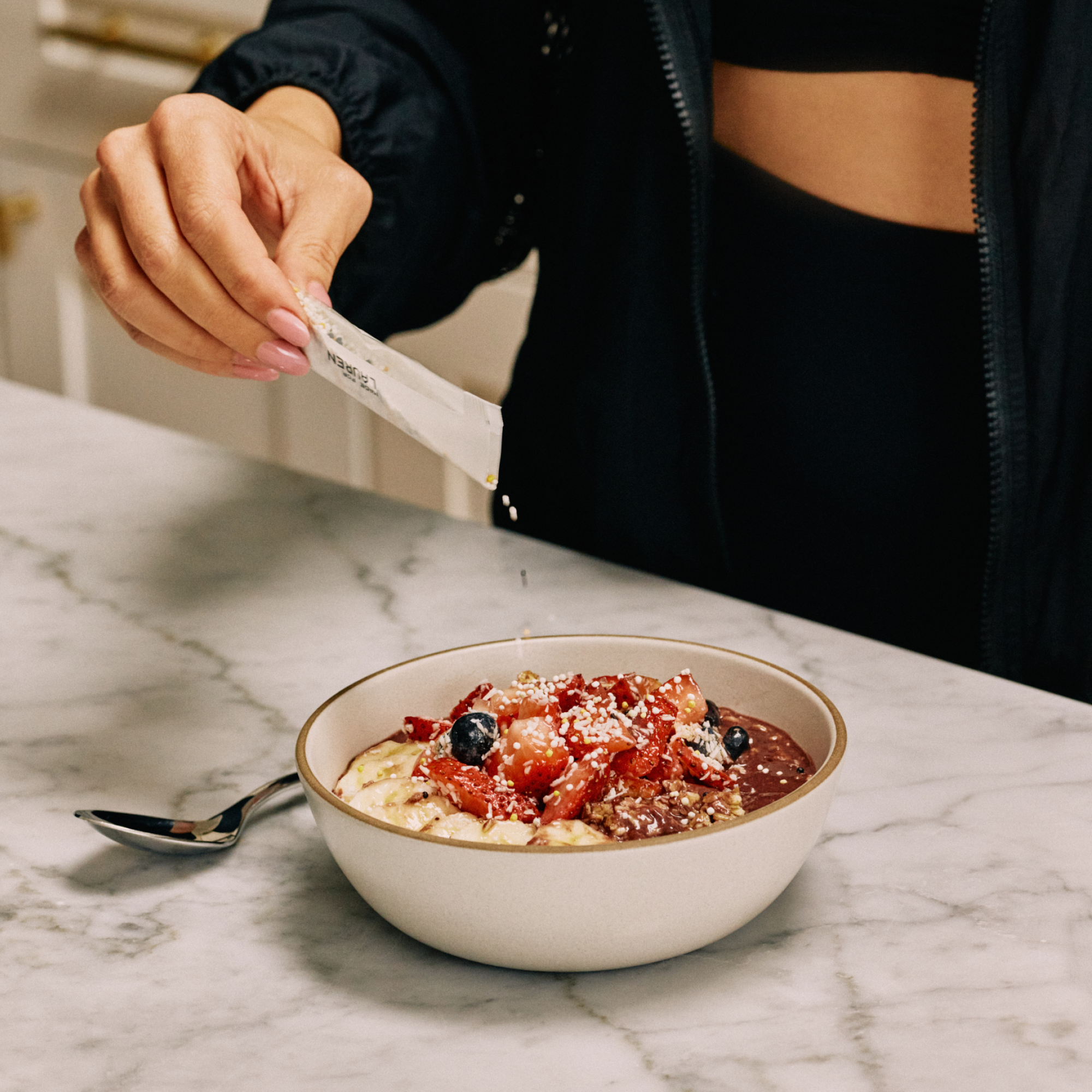 Woman pouring Smart Multivitamin packet in smoothie bowl