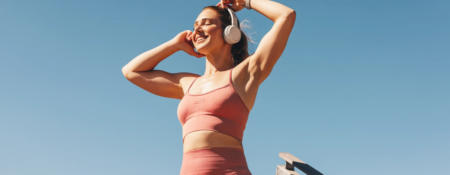 Woman smiling in workout clothes and wearing headphones