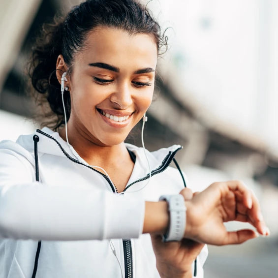 Woman smiling wearing headphones and using watch