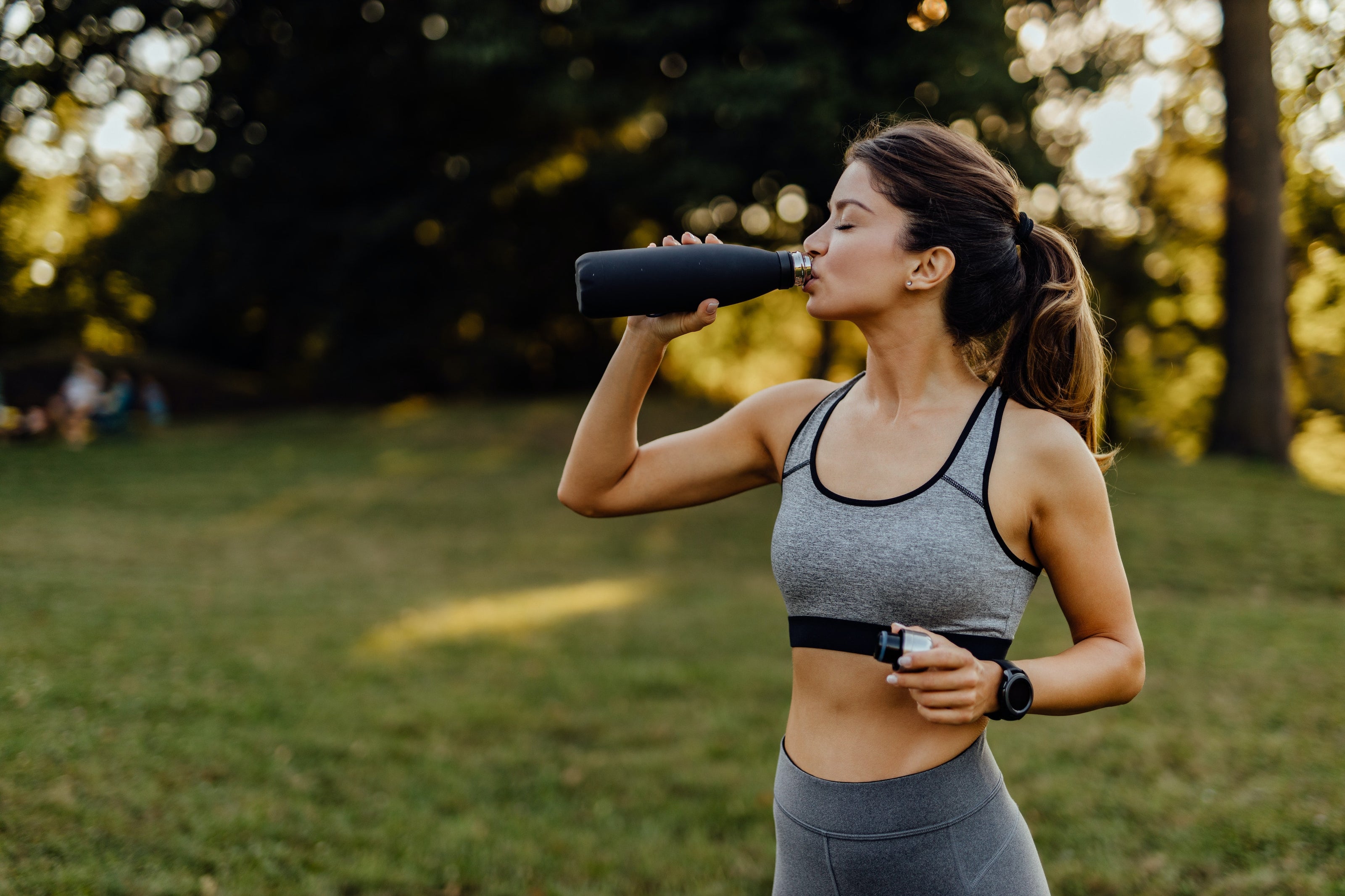 Woman in exercise clothes drinking out of water bottle